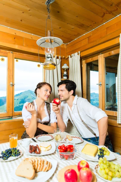 Young couple in mountain chalet eating — Stock fotografie