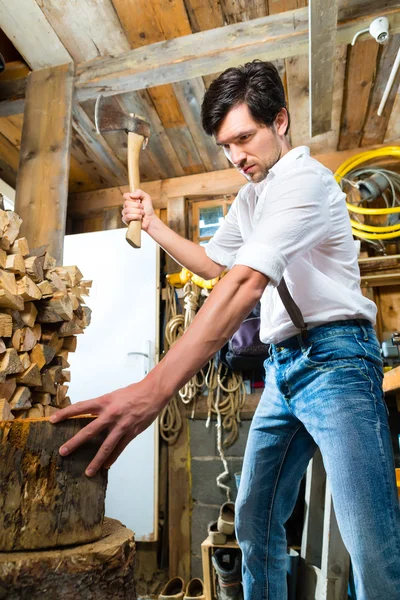 Young man chopping fire wood in mountain chalet — 스톡 사진