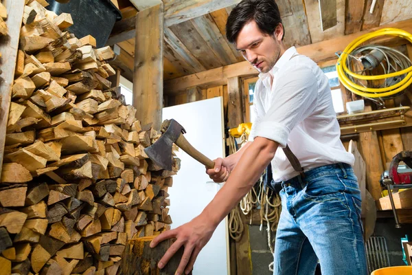 Young man chopping fire wood in mountain chalet — 스톡 사진