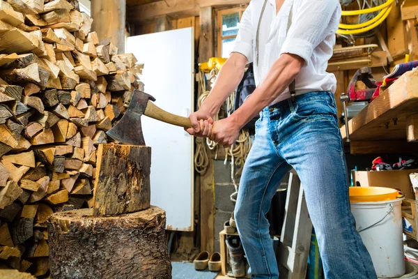 Junger Mann hackt Feuerholz in Berghütte — Stockfoto
