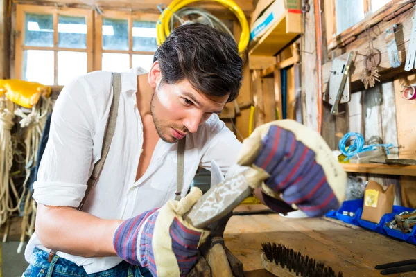 Young man sharpening tools in mountains hut — Stock Fotó