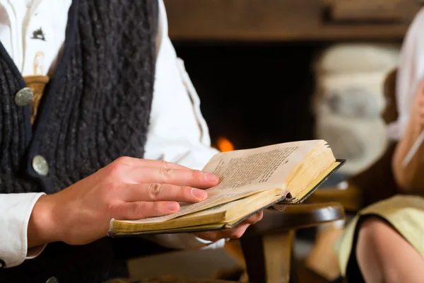 Joven en la cabaña de un cazador leyendo la Biblia — Foto de Stock