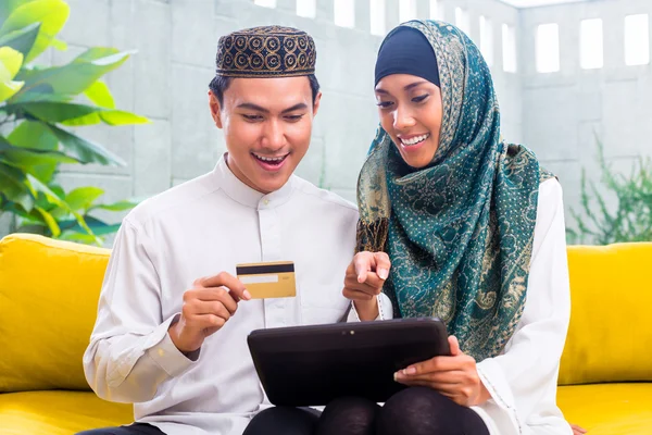Asian Muslim couple shopping online on pad in living room — Stock Photo, Image