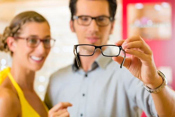 Pareja joven en óptico con gafas — Foto de Stock