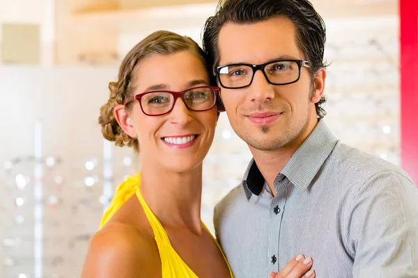 在配镜师戴着眼镜的年轻夫妇 — 图库照片