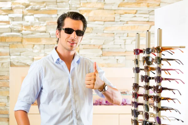 Fiatal ember, a napszemüveget vásárol látszerész — Stock Fotó