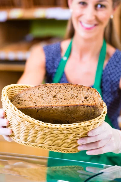 Bakery saleswoman offering bread — Stock Photo, Image