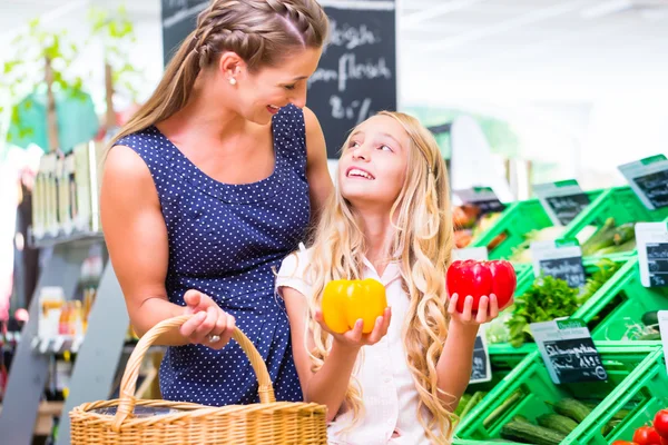 Matka a dcera výběr zeleniny v supermarketu — Stock fotografie