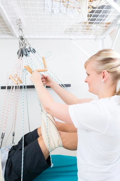 Fysiotherapeut met patiënt op sling tabel — Stockfoto