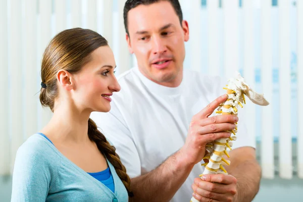 Physiotherapist in his practice, he explains a female patient — Stock Photo, Image