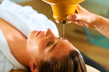 Woman enjoying a Ayurveda oil massage clipart