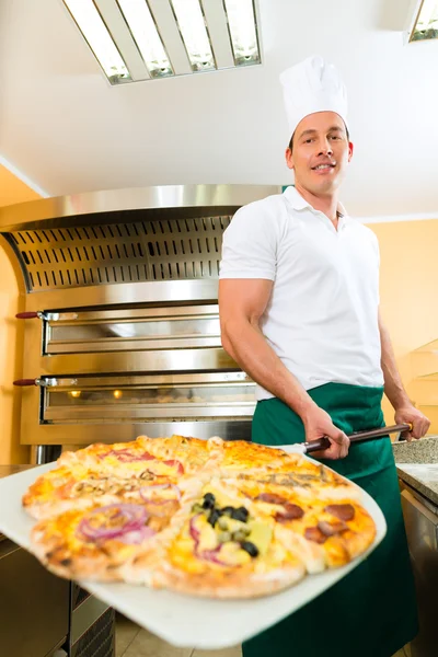 Muž tlačí hotové pizzy z pece — Stock fotografie