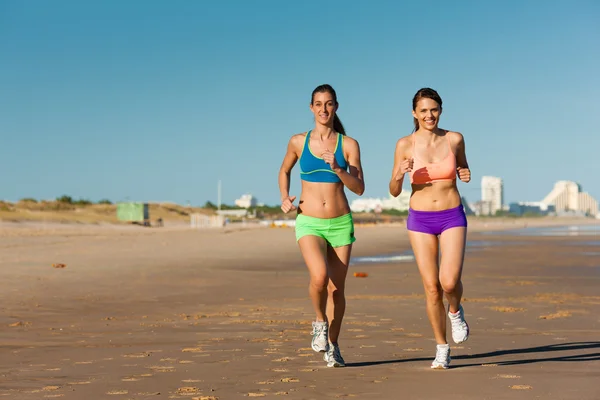 Sport- och Fitness - folk jogga på stranden — Stockfoto