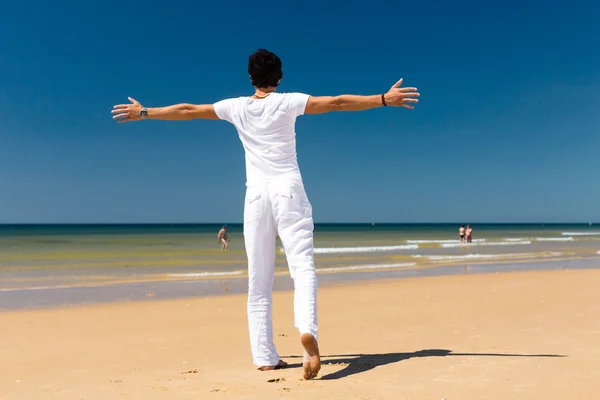 Bonito homem de pé ao sol na praia — Fotografia de Stock