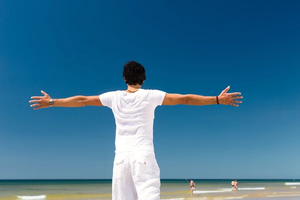 Bonito homem de pé ao sol na praia — Fotografia de Stock