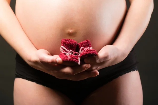 Pregnant woman and baby shoes — Stock Photo, Image