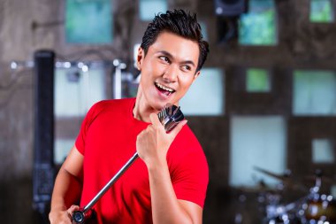 Asian singer producing song in recording studio clipart