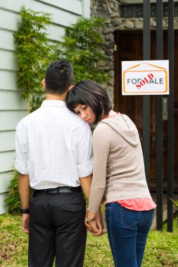 disappointed asian couple in front of a house clipart