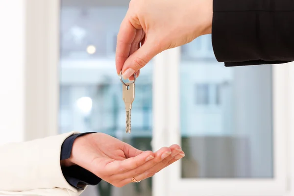 Jovem corretor de imóveis está com chaves em um apartamento — Fotografia de Stock