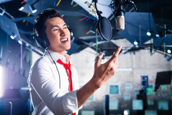 Cantante asiático masculino produciendo canción en estudio de grabación — Foto de Stock