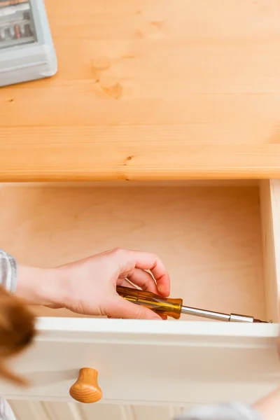 Jonge vrouw is het samenstellen van een kast — Stockfoto