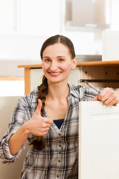 Young woman is assembling a cupboard — Stock Photo, Image