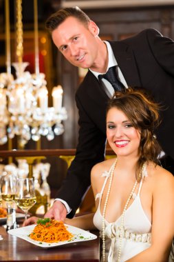 Beautiful woman and waiter in fine dining restaurant