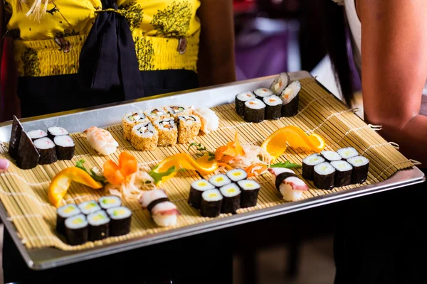 Garçonete com sushi no restaurante asiático — Fotografia de Stock