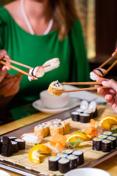 Jovens comendo sushi no restaurante asiático — Fotografia de Stock