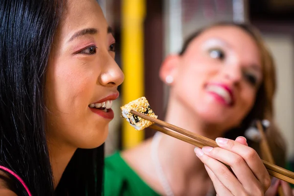 Young people eating sushi in Asian restaurant — Stock Photo, Image