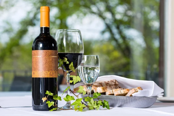 Kırmızı şarap şişe ve cam bir tablo ile — Stok fotoğraf