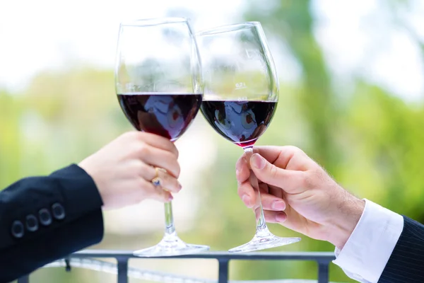 Mãos segurando copos de vinho tinto para clink — Fotografia de Stock