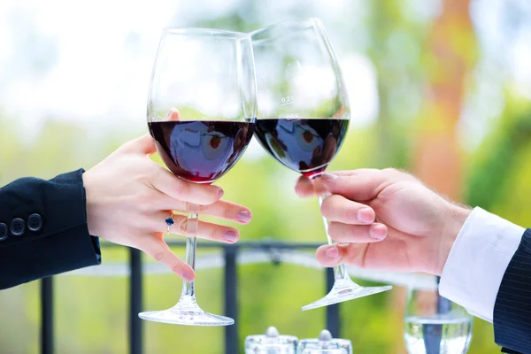 Mãos segurando copos de vinho tinto para clink — Fotografia de Stock