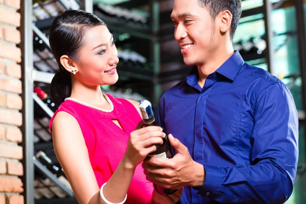 Asian couple holding wine bottle in restaurant — Stock Photo, Image