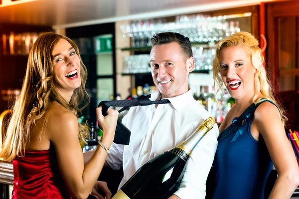 Glückliche Freunde mit einer Flasche Champagner an der Bar — Stockfoto
