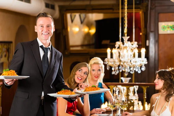 Freunde im Restaurant, Kellner serviert das Abendessen — Stockfoto