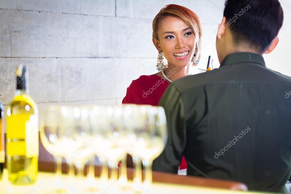 Asian couple drinking white wine in bar