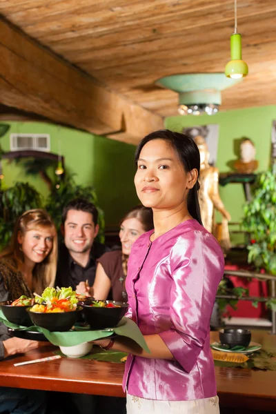 Personas con camarera comiendo en restaurante tailandés — Foto de Stock