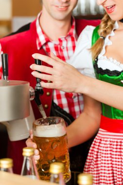 Young woman drawing beer in restaurant or pub