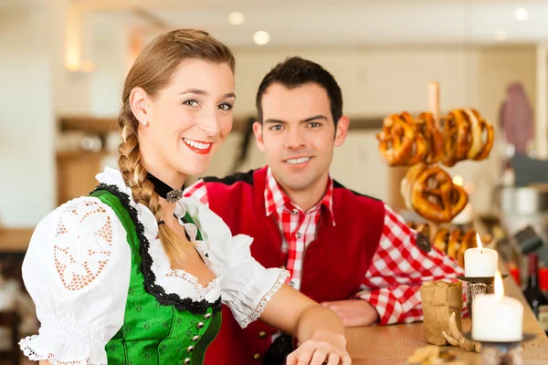 Casal jovem em Tracht tradicional da Baviera em restaurante ou pub — Fotografia de Stock