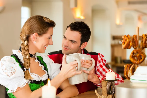 Casal jovem em Tracht tradicional da Baviera em restaurante ou pub — Fotografia de Stock