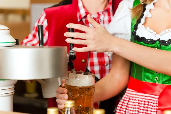 Young woman drawing beer in restaurant or pub — Stock fotografie