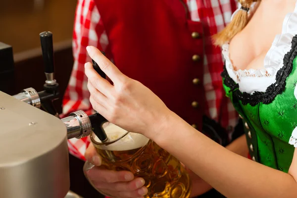 Young woman drawing beer in restaurant or pub — Stok fotoğraf