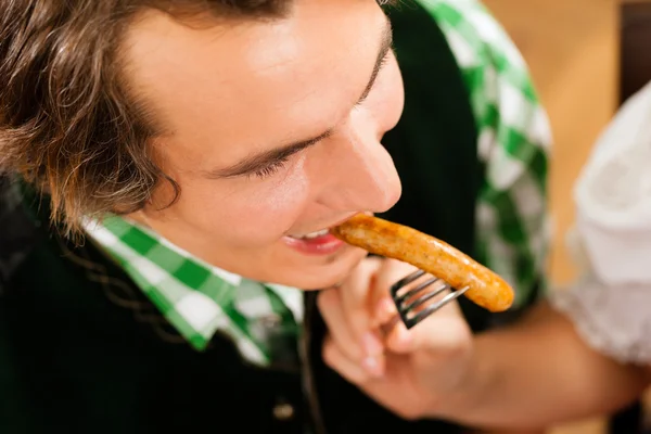 Uomo in ristorante o pub mangiare salsiccia — Foto Stock