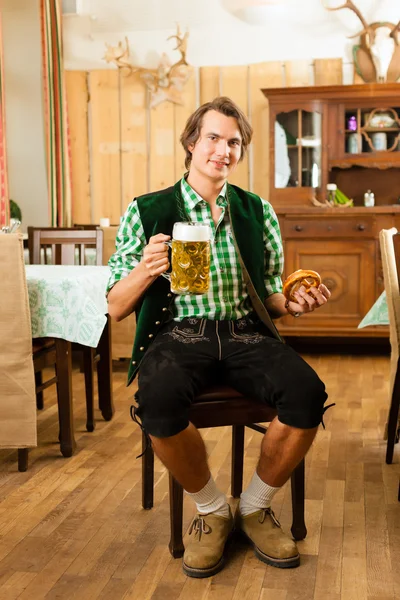 Человек в традиционной баварской трахте в ресторане или пабе — стоковое фото