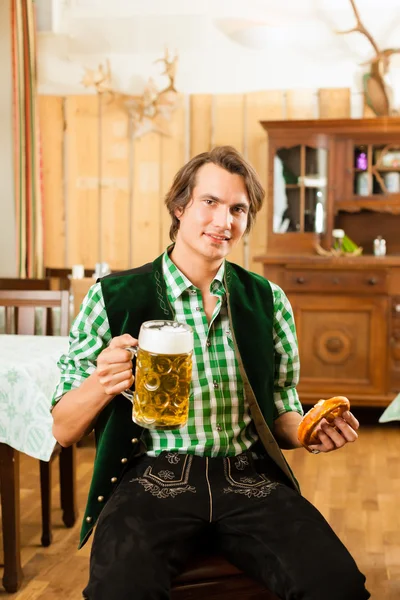 Человек в традиционной баварской трахте в ресторане или пабе — стоковое фото