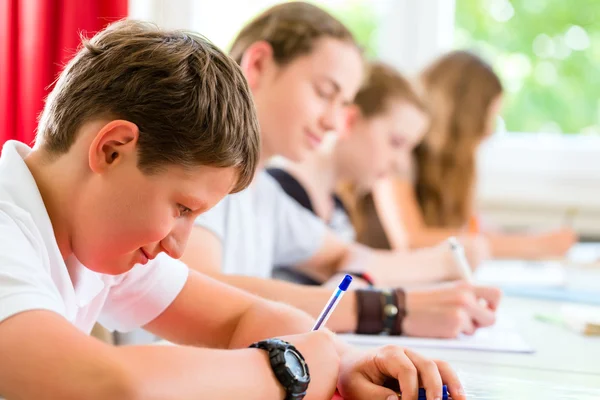 Estudiantes que escriben una prueba en la escuela concentrándose —  Fotos de Stock