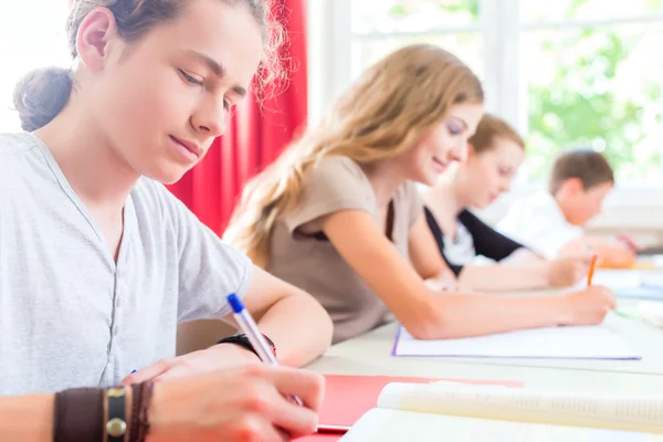 Estudiantes que escriben una prueba en la escuela concentrándose —  Fotos de Stock