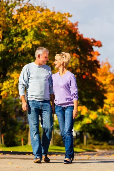 Seniors in autumn or fall walking hand in hand — Stock Photo, Image