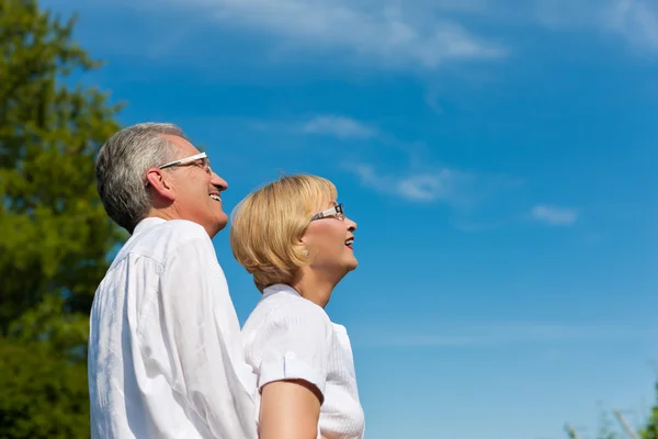 Szczęśliwa para dojrzałych lub starszy patrząc na błękitne niebo — Zdjęcie stockowe